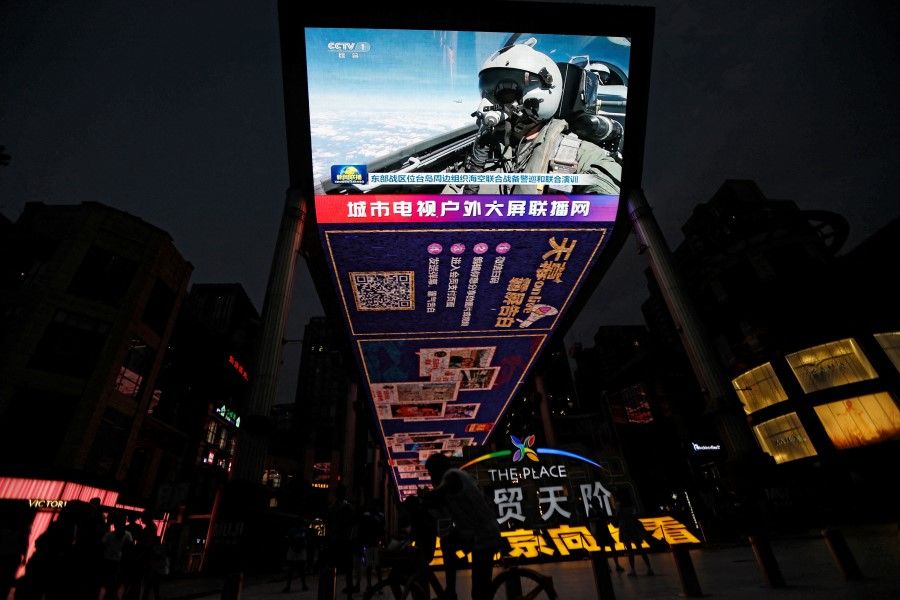 A screen broadcasts news footage of an Air Force aircraft taking part in military drills by the Eastern Theatre Command of China's People's Liberation Army (PLA) around Taiwan, in a shopping area in Beijing, China, on 19 August 2023. (Tingshu Wang/Reuters)