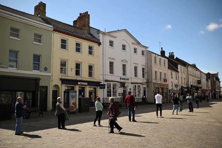 People observe social distancing guidelines as they queue to enter shops and banks in Pontefract, northern England, April 27, 2020. (Oli Scarff/AFP)