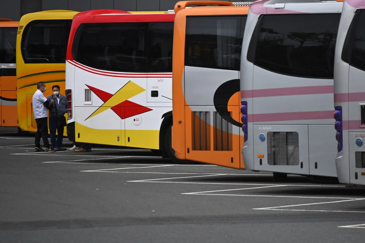 Employees of cross border bus companies stand at the bus stop of Shenzhen Bay Port (Hong Kong Port Area) on 8 February 2020. Hong Kong began enforcing a mandatory 14-day mandatory quarantine for anyone arriving from mainland China in a bid to stop the deadly new coronavirus from spreading. (Philip Fong/AFP)
