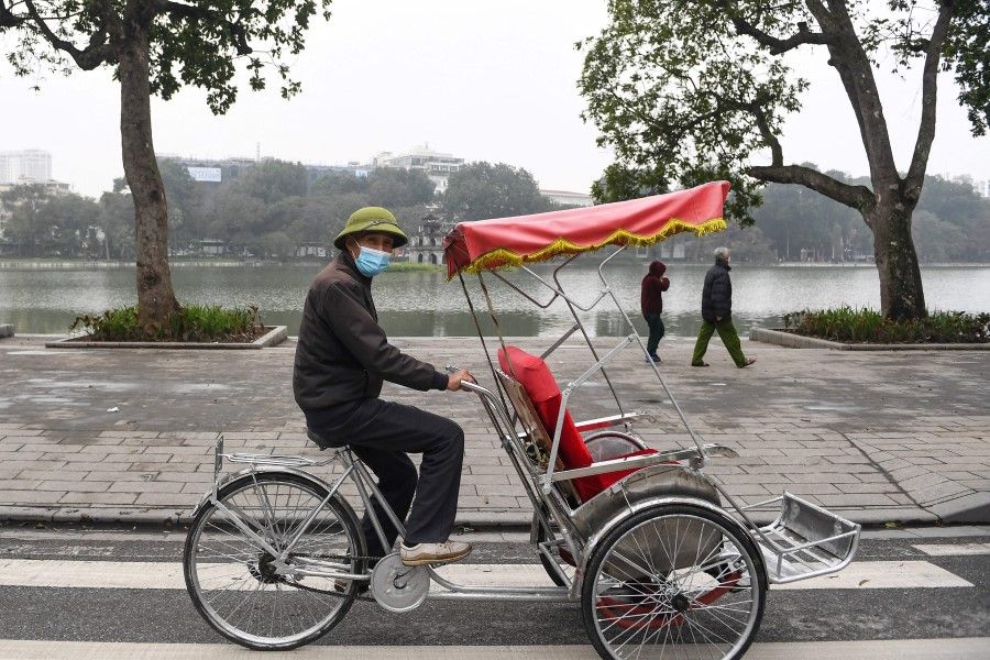 A cyclo driver looks for customers along Hoan Kiem Lake in downtown Hanoi on 16 February 2022. (Nhac Nguyen/AFP)