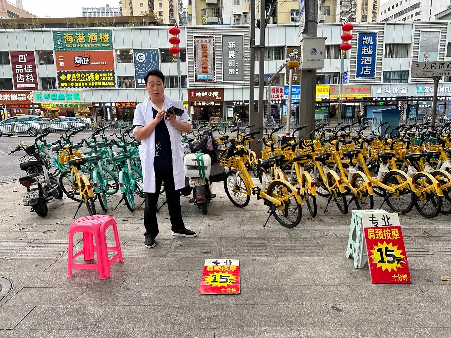 With just a folding chair, white coat, and promotional sign, anyone can be a “street masseur”.
