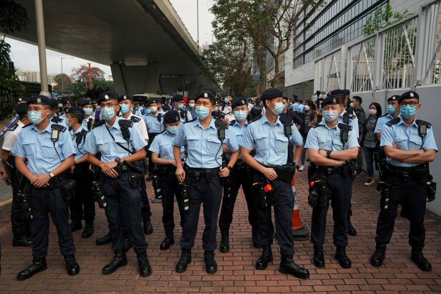 Police officers stand as supporters of pro-democracy activists facing charges related to national security gather outside West Kowloon Magistrates' Courts, in Hong Kong, 1 March 2021. (Lam Yik/Reuters)