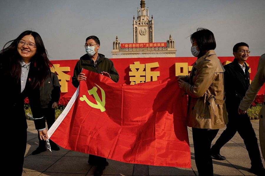 People hold a flag of the Communist Party of China at the Beijing Exhibition Center ahead of the 20th Party Congress meeting in Beijing, China, on 12 October 2022. (Noel Celis/AFP)