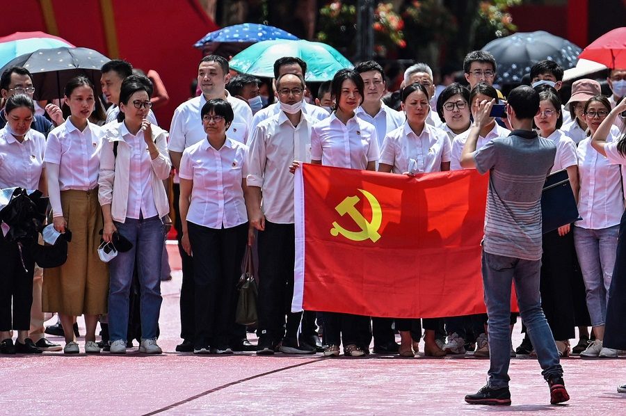People pose for a picture with a flag of the Communist Party of China next to the First National Congress of the Chinese Communist Party in Shanghai, China, on 1 July 2021, as the country marks the 100th anniversary of the founding of the party. (Hector Retamal/AFP)