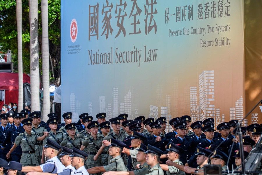 Attendees from various forces march next to a banner supporting the new national security law at the end of a flag-raising ceremony to mark the 23rd anniversary of Hong Kong's handover from Britain in Hong Kong on 1 July 2020. (Anthony Wallace/AFP)