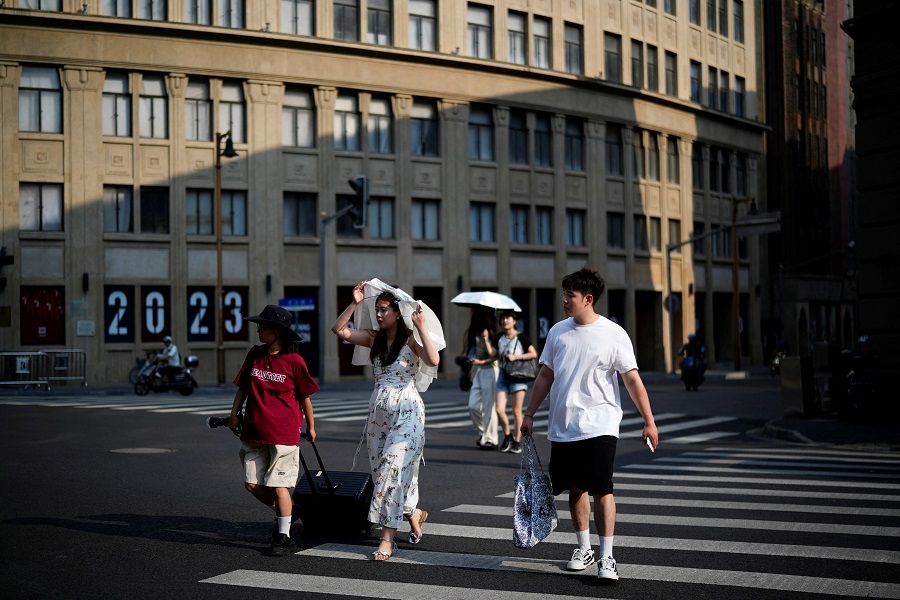 People cross a street in Shanghai, China, 10 August 2023. (Aly Song/Reuters)