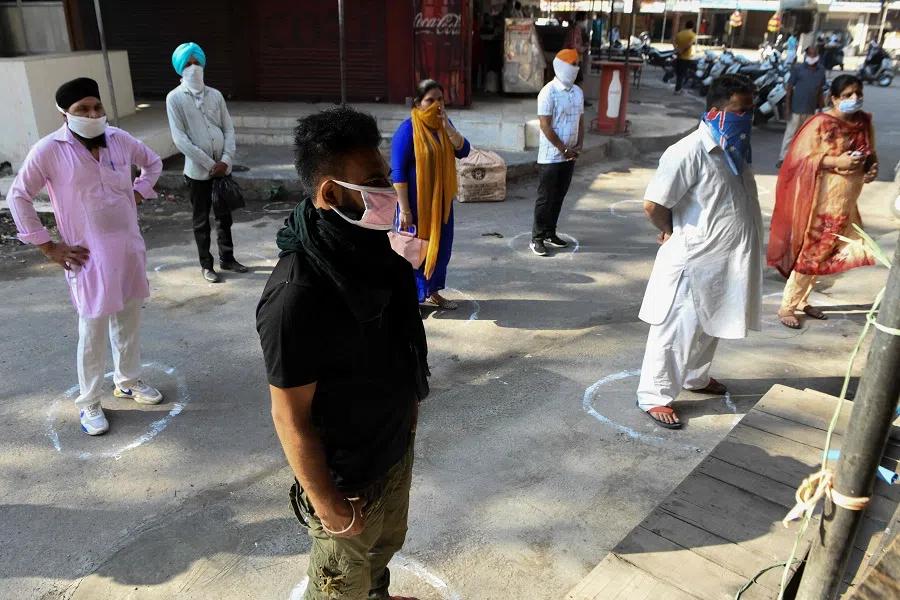 Customers stand inside marked circles to maintain social distancing as they wait outside a shop after the government eased a nationwide lockdown imposed as a preventive measure against the Covid-19 coronavirus, in Amritsar, India, on 12 May 2020. (Narinder Nanu/AFP)