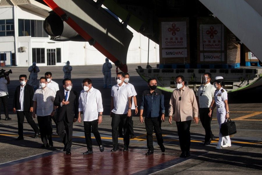 Philippine President Rodrigo Duterte and Chinese Ambassador Huang Xilian walk away from a Chinese military aircraft carrying the first batch of Sinovac Biotech's CoronaVac, the first shipment of coronavirus disease (COVID-19) vaccines to arrive in the country, at Villamor Air Base, Pasay, Metro Manila, Philippines, 28 February 2021. (Eloisa Lopez/Reuters)