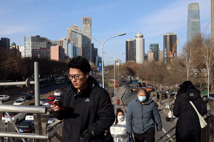 People walk on a pedestrian bridge at the central business district in Beijing, China, on 29 February 2024. (Florence Lo/Reuters)