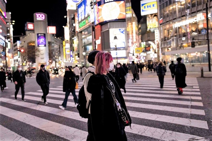 People wearing face masks walk at Shibuya district in Tokyo, Japan, on 19 January 2022. (Behrouz Mehri/AFP)