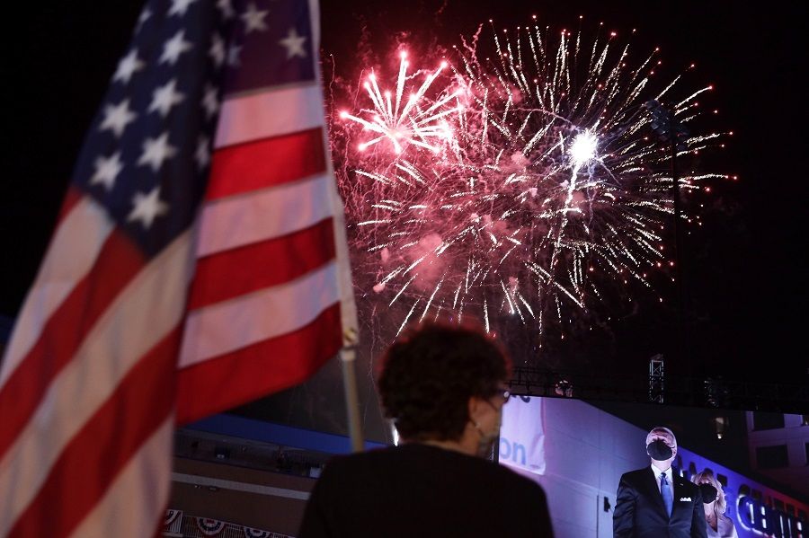 Democratic presidential nominee Joe Biden and his wife Jill Biden are seen on a screen as supporters watch fireworks during the Democratic National Convention at a parking lot outside Chase Center on 20 August 2020 in Wilmington, Delaware. (Alex Wong/Getty Images/AFP)