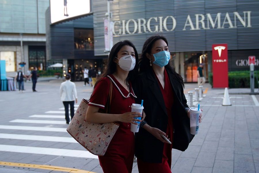 People wearing face masks walk past a Giorgio Armani store at a shopping complex in Beijing, China, 19 September 2020. (Tingshu Wang/Reuters)