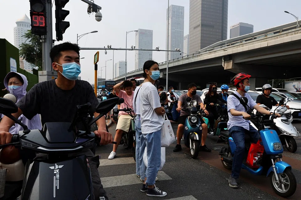 People wait at an intersection on a street during morning rush hour, in Beijing's central business district, China, 2 August 2022. (Tingshu Wang/Reuters)
