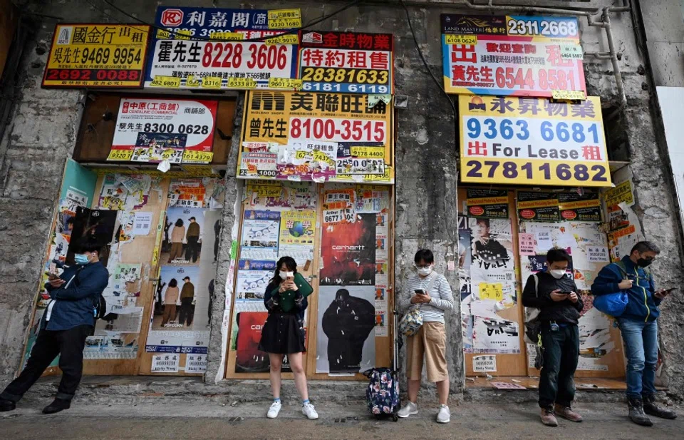 People use their mobile phones outside a closed down business in Hong Kong on 1 November 2022. (Peter Parks/AFP)