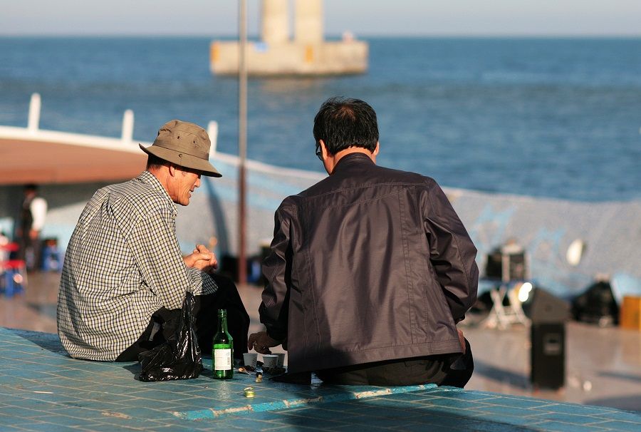 Two men drink soju on the Busan waterfront in South Korea. (iStock)