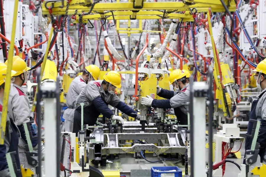 This photo taken on 14 January 2023 shows employees working on a car assembly line at a Beijing Automotive factory in Qingdao, in China's eastern Shandong province. (AFP)
