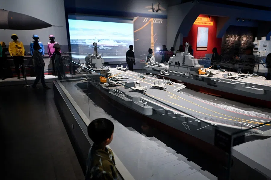 This picture taken during a media tour organised by the PLAN to mark its 75th founding anniversary, shows a child looking at a model of the Chinese Navy Shandong aircraft carrier (L) at the PLA Naval Museum in Qingdao, China’s Shandong province, on 23 April 2024. (Wang Zhao/AFP)