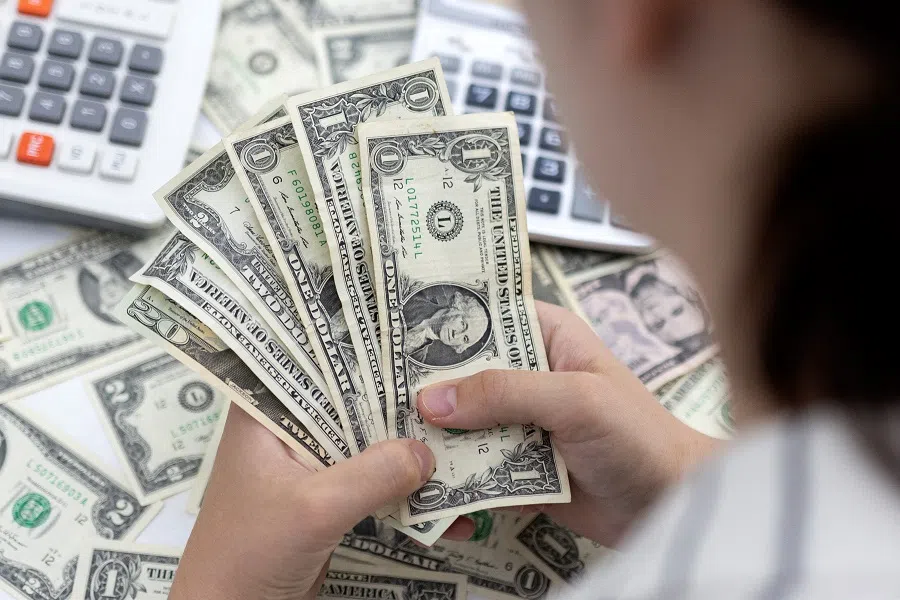 A woman holds US dollar banknotes in this illustration taken 30 May 2022. (Dado Ruvic/Illustration/Reuters)