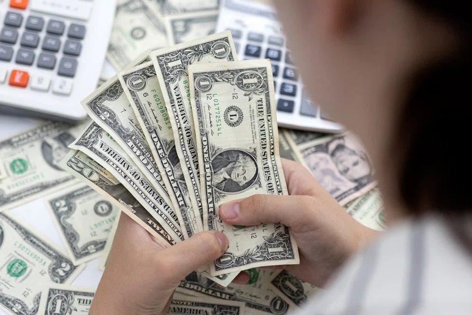 A woman holds US dollar banknotes in this illustration taken 30 May 2022. (Dado Ruvic/Illustration/Reuters)