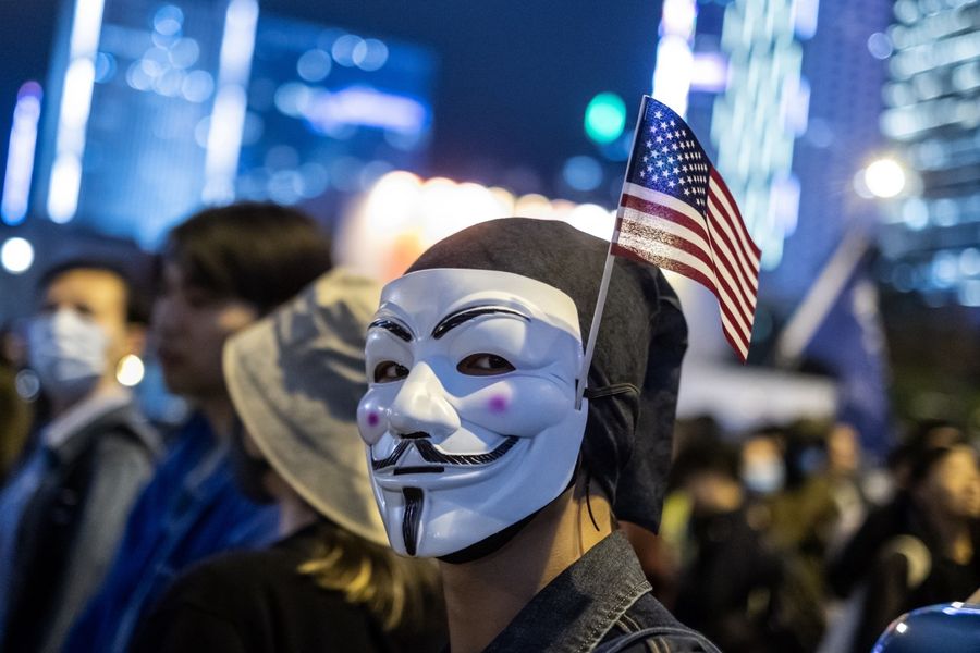A demonstrator wears an anonymous mask, also known as a Guy Fawkes mask, and an American flag during the "Thanksgiving Day Assembly for Hong Kong Human Rights and Democracy Act" at Edinburgh Place in the Central district of Hong Kong, China, on Thursday, Nov. 28, 2019. (Justin Chin/Bloomberg)