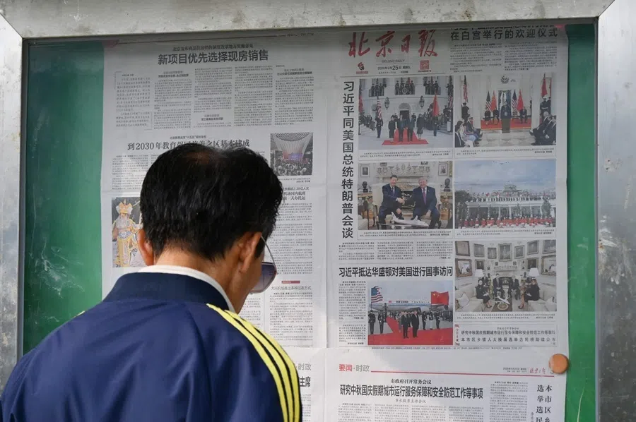 A man reads a newspaper at a display board in Beijing on 25 September 2026.