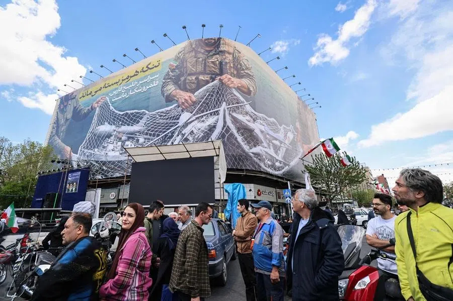 Iranians walk past a large billboard reading "The Strait of Hormuz remains closed" as people gather in Tehran's Revolution Square after the US and Iran agreed to a two-week ceasefire, on 8 April 2026. (Atta Kenare/AFP)