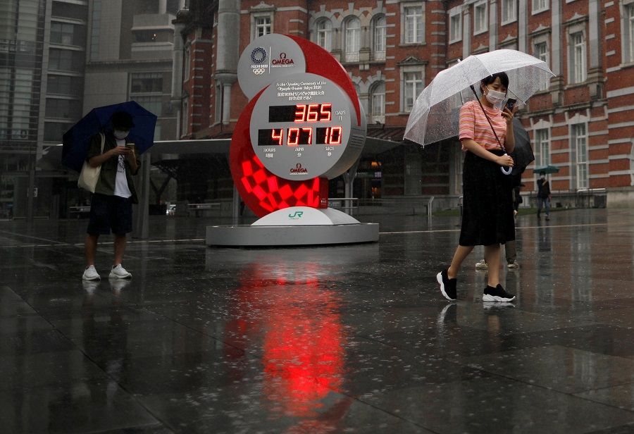 Passersby wearing protective face masks walk past a countdown clock for the Tokyo 2020 Olympic Games that have been postponed to 2021 due to the Covid-19 coronavirus outbreak, in Tokyo, Japan, 23 July 2020. (Issei Kato/Reuters)