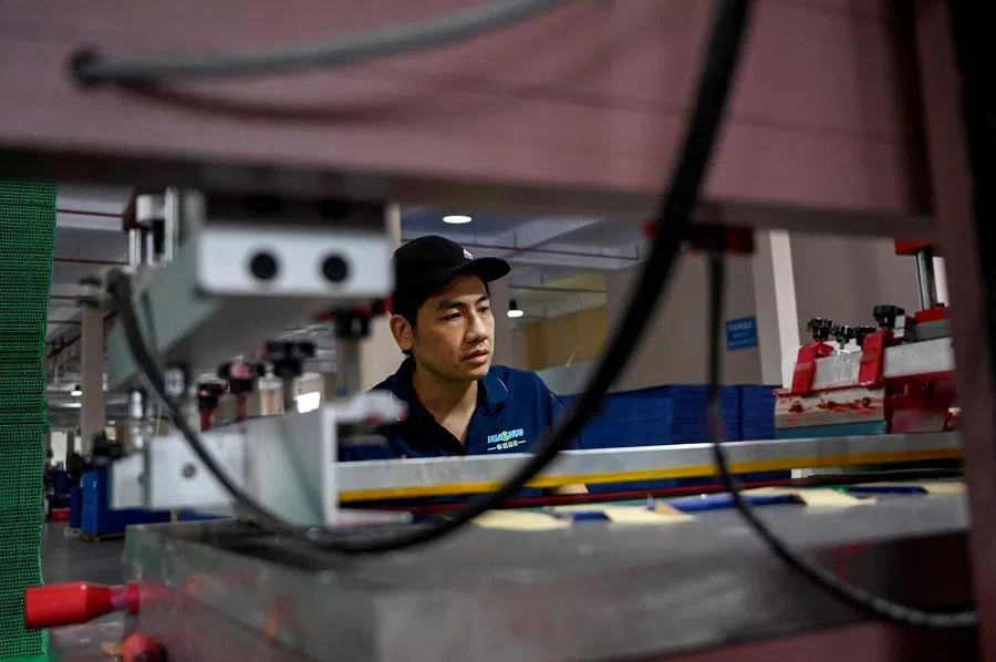 This photo taken on 28 July 2025 shows a worker operating a plastic sheet production machine at a factory in Hai Phong, Vietnam.