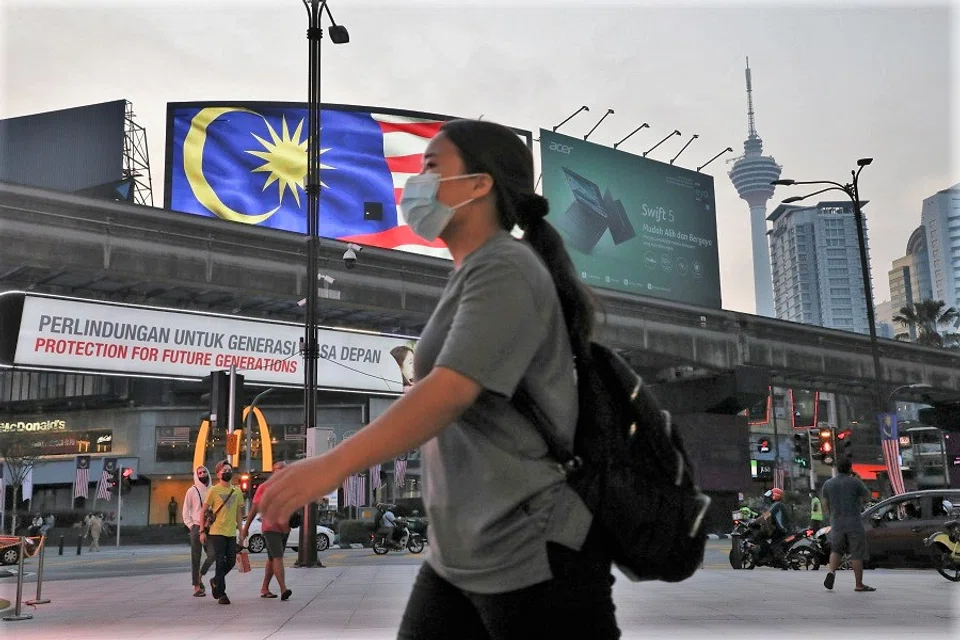 People wearing protective masks cross a street outside a shopping mall in Kuala Lumpur, Malaysia, 6 September 2021. (Lim Huey Teng/Reuters)