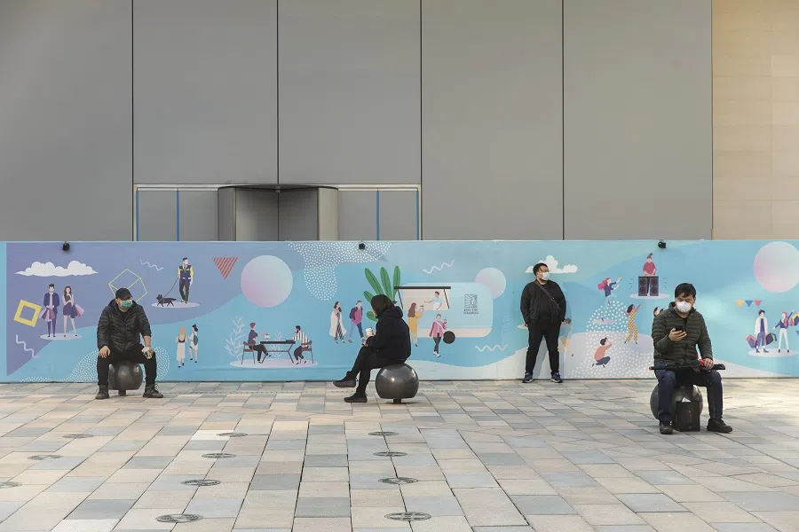 People wearing protective masks sit in a square at the Taikoo Li Sanlitun shopping area in Beijing, China, on 17 March 2020. (Qilai Shen/Bloomberg)