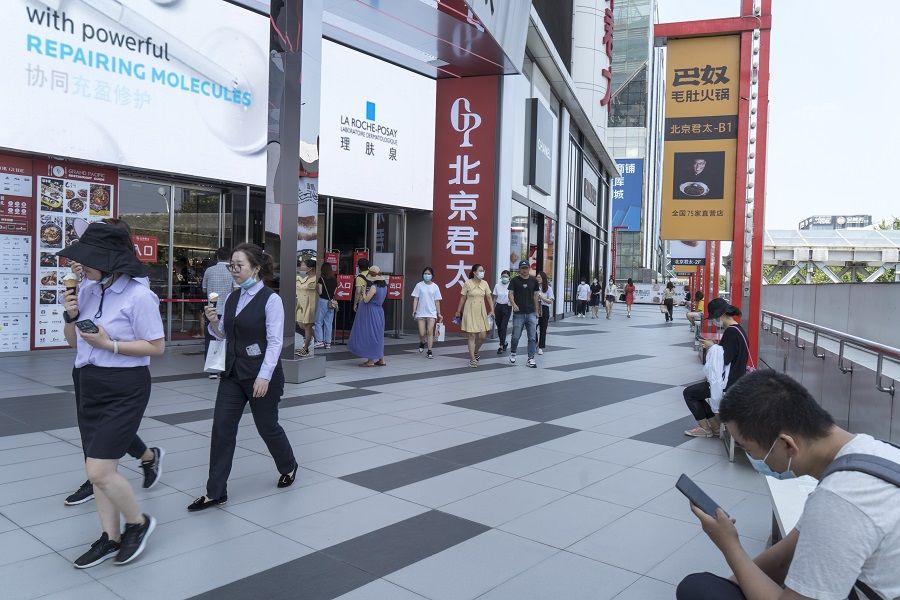 Pedestrians wearing protective masks walk past stores in the Xidan shopping area in Beijing, China, on 15 July 2020. (Giulia Marchi/Bloomberg)