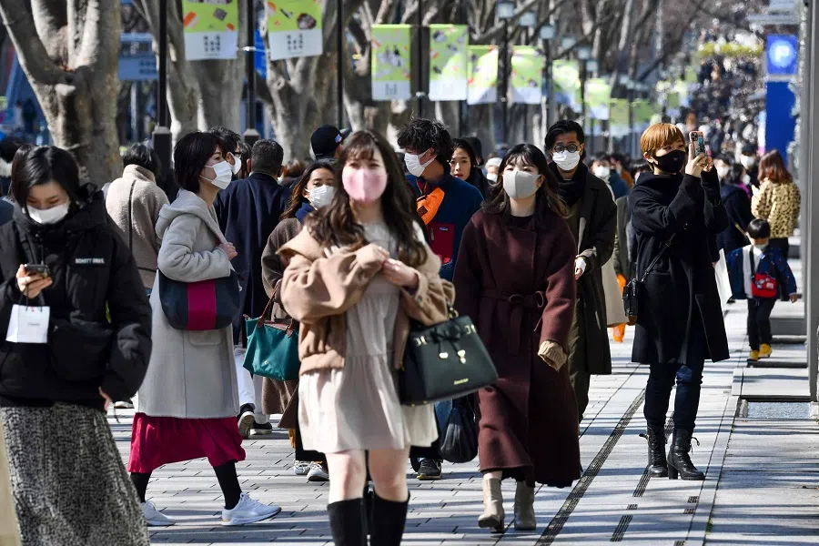 People wearing face masks walk along a street in the Harajuku shopping district in Tokyo on 27 February 2021. (Kazuhiro Nogi/AFP)