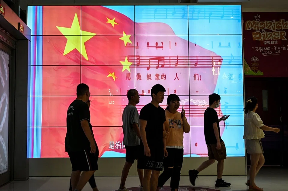 People walk past a screen showing a Chinese national flag at a shopping mall in Beijing, China, on 26 May 2023. (Jade Gao/AFP)