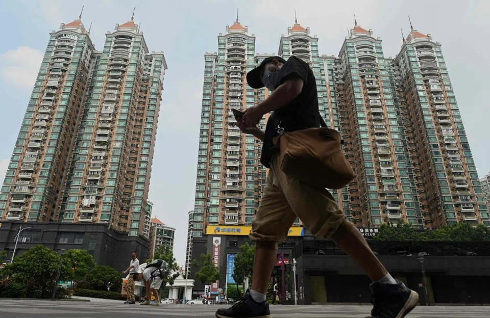 This file photo taken on 17 September 2021 shows a man walking past a housing complex by Chinese property developer Evergrande in Guangzhou, China's southern Guangdong province. (Noel Celis/AFP)
