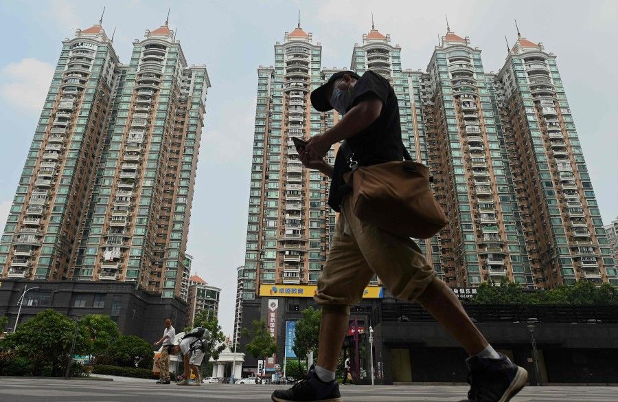 This file photo taken on 17 September 2021 shows a man walking past a housing complex by Chinese property developer Evergrande in Guangzhou, China's southern Guangdong province. (Noel Celis/AFP)