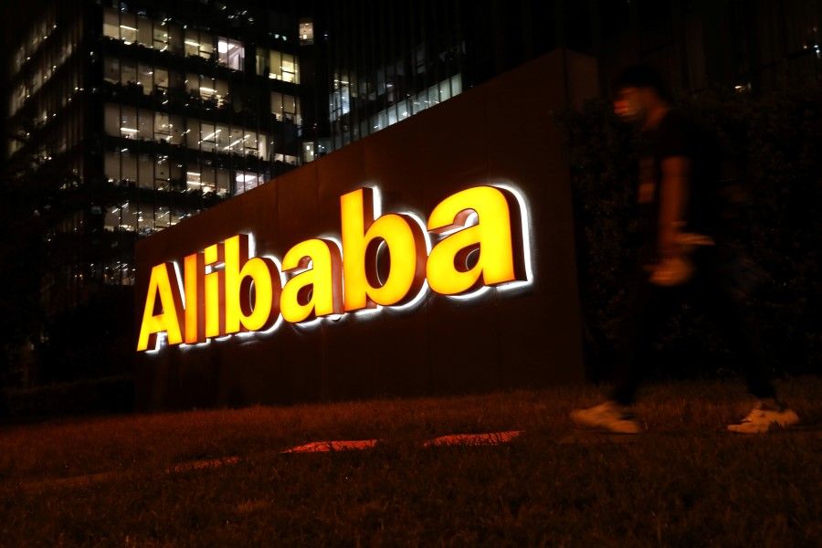 A man walks past a logo of Alibaba Group at its office building in Beijing, China, 9 August 2021. (Tingshu Wang/Reuters)