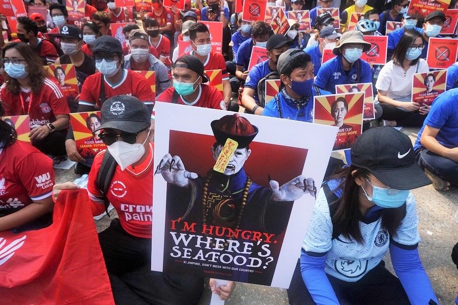 Protesters hold placards as they take part in a demonstration against the military coup, in front of the Chinese embassy in Yangon on 21 February 2021. (Sai Aung Main/AFP)