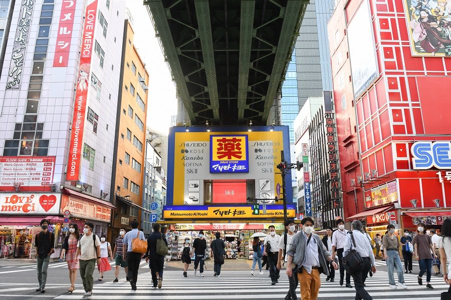 Pedestrians cross a street in front of a Matsumotokiyoshi Co. store built under railway tracks in Tokyo, Japan, on 3 September 2020. (Noriko Hayashi/Bloomberg)