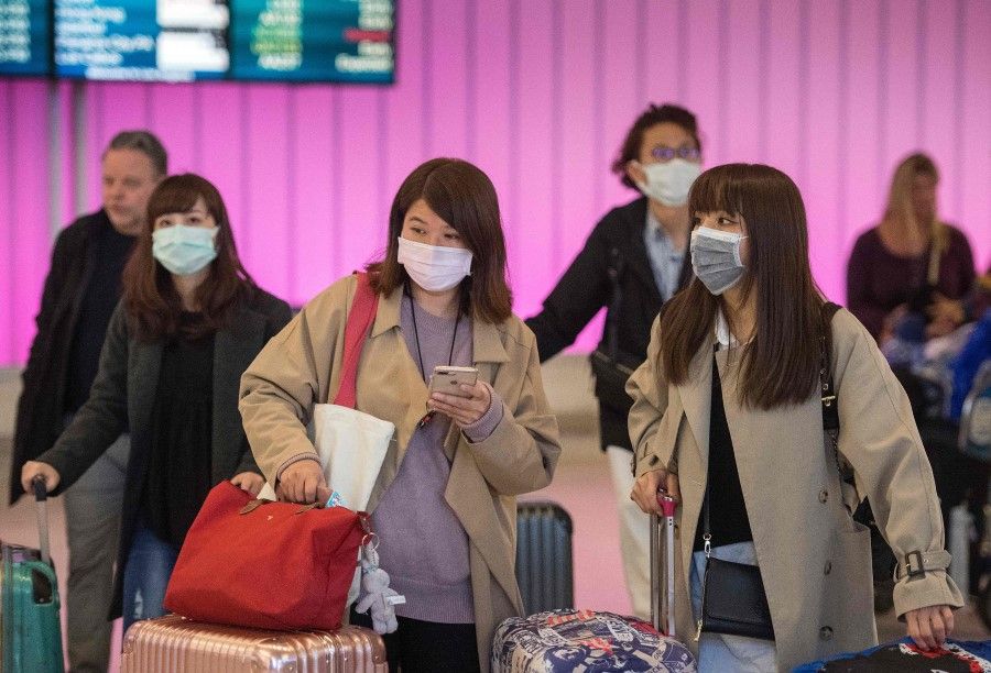 Passengers wear protective masks to protect against the spread of the Coronavirus as they arrive at the Los Angeles International Airport, California, on January 22, 2020. (Mark Ralston/AFP)