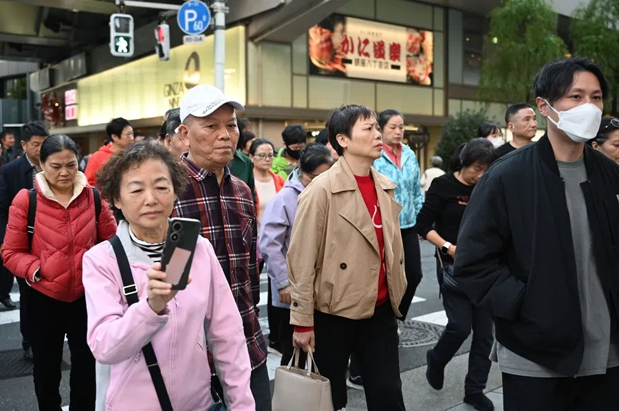 Members of a Chinese tour group cross a road in the Ginza shopping district in Tokyo on 17 November, 2025. (Greg Baker/AFP)