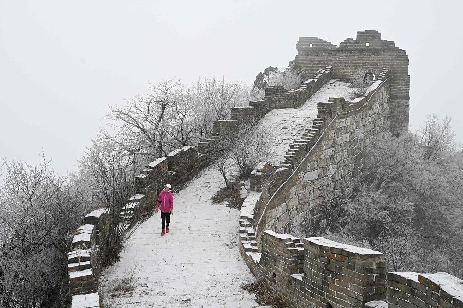 A woman walks the Great Wall of China after a light snowfall at Jiankou, Beijing, China on 9 January 2022. (Greg Baker/AFP)