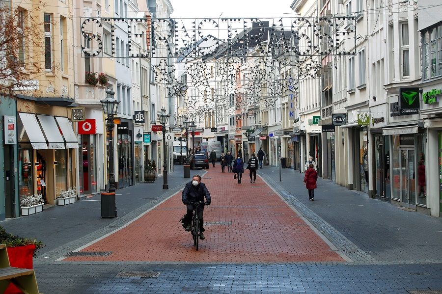 A man rides a bike through an almost deserted Sternstrasse (Star street) shopping street, in Bonn, Germany, 16 December 2020. (Wolfgang Rattay/Reuters)