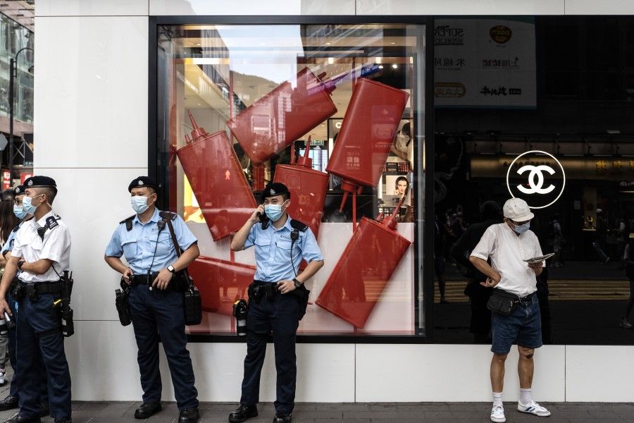 Police officers stand guard outside a Chanel Ltd. store in the Causeway Bay area of Hong Kong on 1 July 2021. Hong Kong's leader pledged to press ahead with an unprecedented national security crackdown, as the Asian financial center marked a series of fraught anniversaries symbolizing Beijing's tightening grip over local affairs. (Chan Long Hei/Bloomberg)