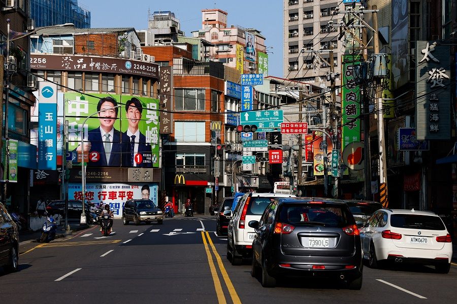 People ride past a campaign ad for William Lai Ching-te, Taiwan's vice-president and the ruling Democratic Progressive Party's (DPP) presidential candidate and Justin Wu, local parliament member candidate for the ruling DPP ahead of the election in Taipei, Taiwan, on 12 January 2024. (Ann Wang/Reuters)
