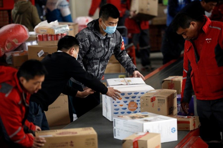 Employees wearing masks following the coronavirus disease (COVID-19) outbreak sort parcels on a conveyor belt at a JD.com's smart logistics center on Singles Day shopping festival, in Beijing, China, 11 November 2020. (Tingshu Wang/REUTERS)