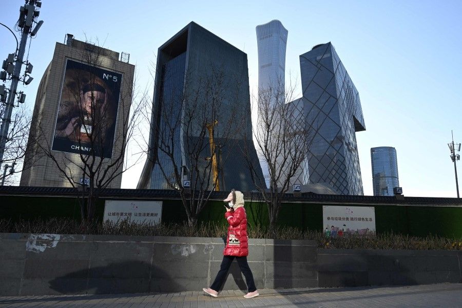 A woman walks on a sidewalk in the central business district in Beijing on 16 December 2021. (Greg BakerAFP)