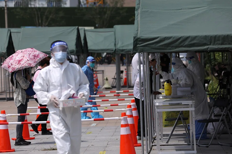 A medical worker collects a swab from a person at a nucleic acid testing site at a park, following new cases of the coronavirus disease, in Beijing, China, 6 August 2021. (Tingshu Wang/Reuters)