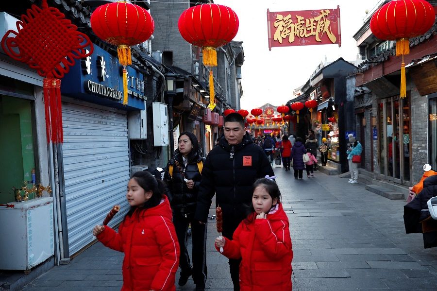 People walk at a hutong alley decorated with lanterns in Beijing, China, 29 January 2022. (Tingshu Wang/Reuters)