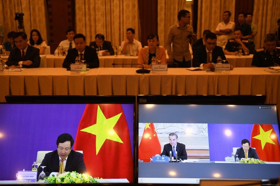 The online meeting between Vietnam's Foreign Minister Pham Binh Minh (L) with his Chinese counterpart Wang Yi (C) is pictured on a monitor during the 12th "Meeting of the China-Vietnam Steering Committee for Bilateral Cooperation", in Hanoi on 21 July 2020. The two countries held the virtual meeting as they seek to mediate a dispute over the South China Sea. (Nhac Nguyen/AFP)
