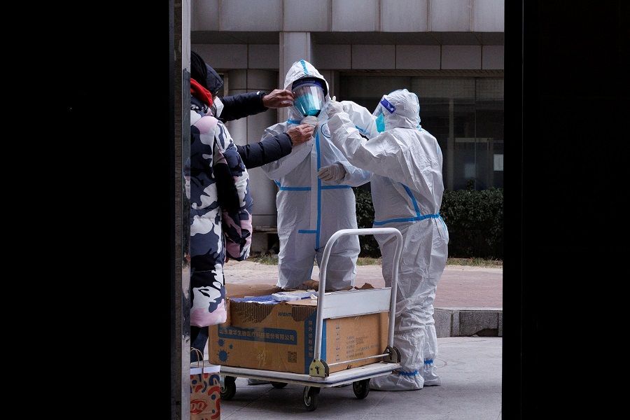 Pandemic prevention workers in protective suits get ready to enter an apartment building that went into lockdown as Covid-19 outbreaks continue in Beijing, China, 2 December 2022. (Thomas Peter/Reuters)